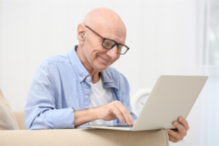 A man with a hearing aid uses a laptop