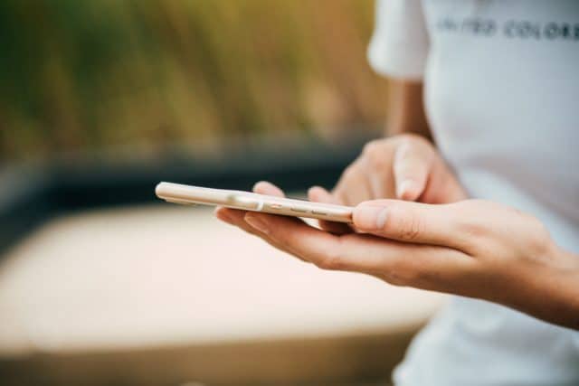 A close up of a person using their smartphone to look at social media.