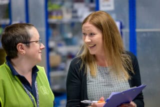 2 women speak to each other in a warehouse