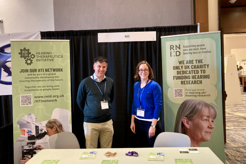 Picture of Dr Ralph Holme, our Director of Research and Insight, and Dr Catherine Perrodin, our Translational Research Manager, at a booth with RNID leaflets