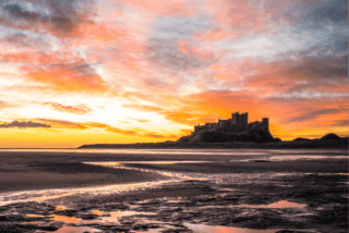 Bamburgh Castle against a sunset on the Northumberland Coast