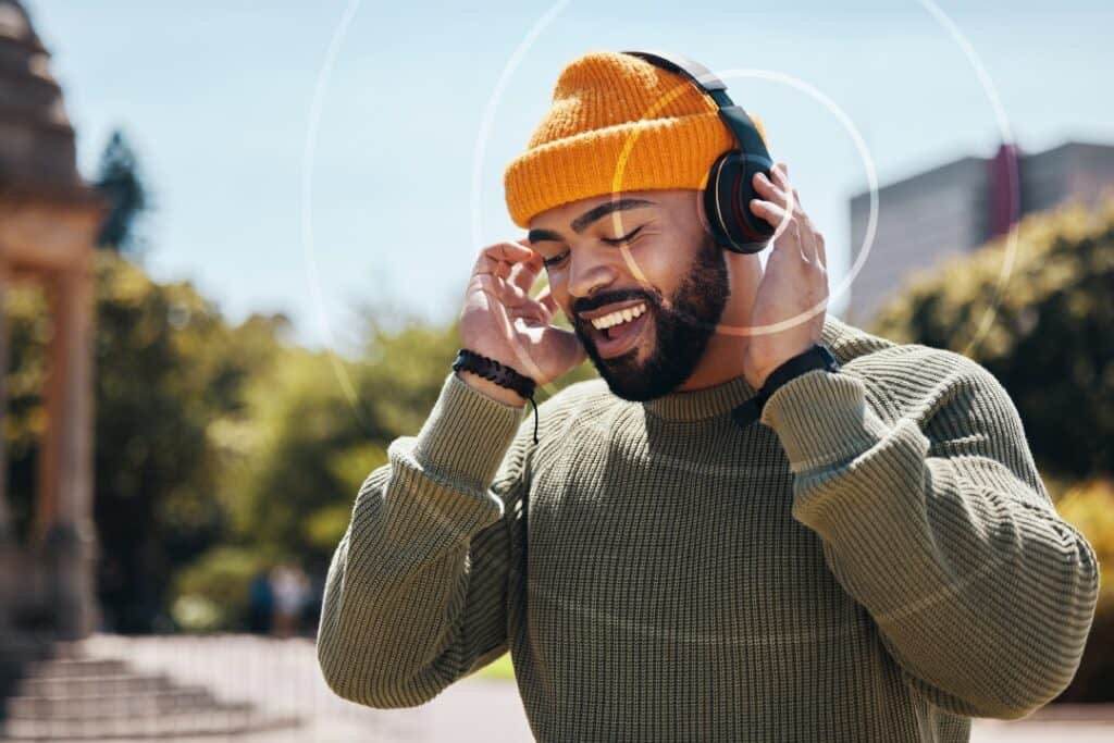 Man smiling wearing a hat and headphones - graphics depicting soundwaves coming from the headphones