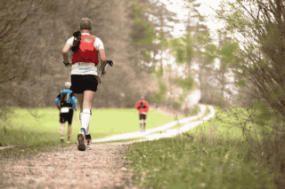 A person trail running in a forest.